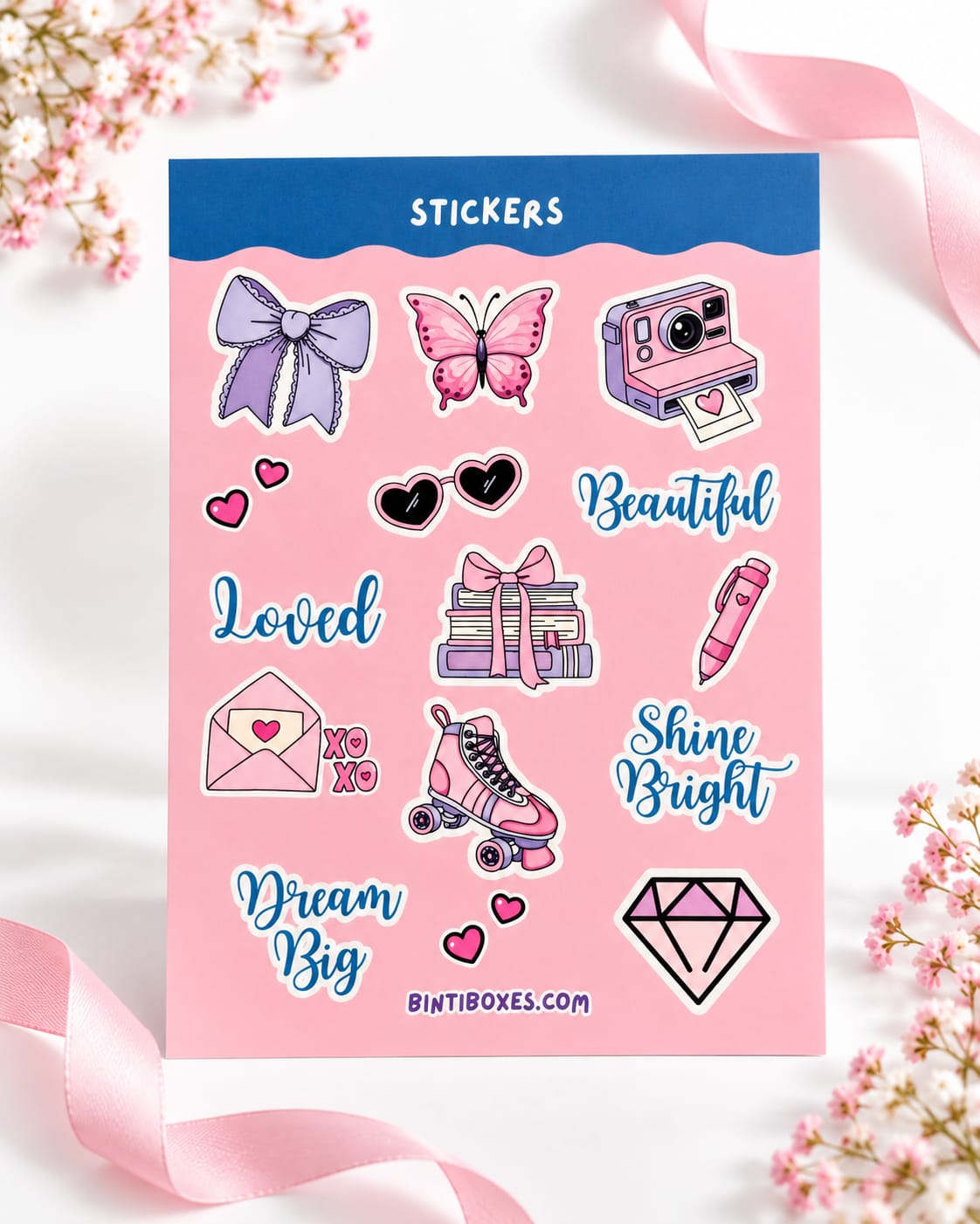 A sheet of pink stickers with various cute illustrations and motivational phrases, displayed on a white surface with pink ribbons and flowers.