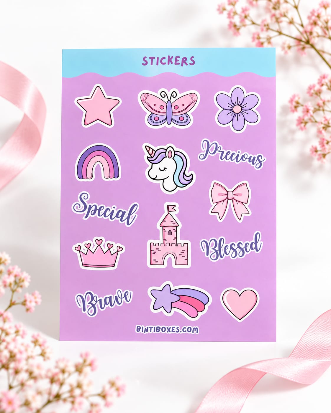 A sheet of pastel stickers displayed on a white background with decorative pink ribbons and flowers. The sticker sheet features whimsical cartoon illustrations including a unicorn, butterfly, rainbow, castle, bow, crown, and text stickers reading 'STICKERS', 'Precious', 'Special', 'Blessed', 'Brave', and 'BINTI BOXES.